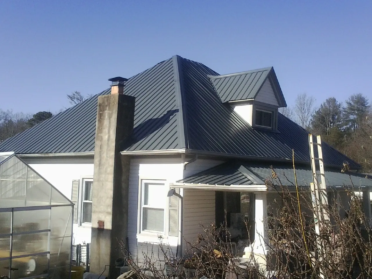 Dark blue standing seam metal roof on a white farmhouse with dormer — Slate & Tile Roof Repair by Roofing Brothers in Mcville