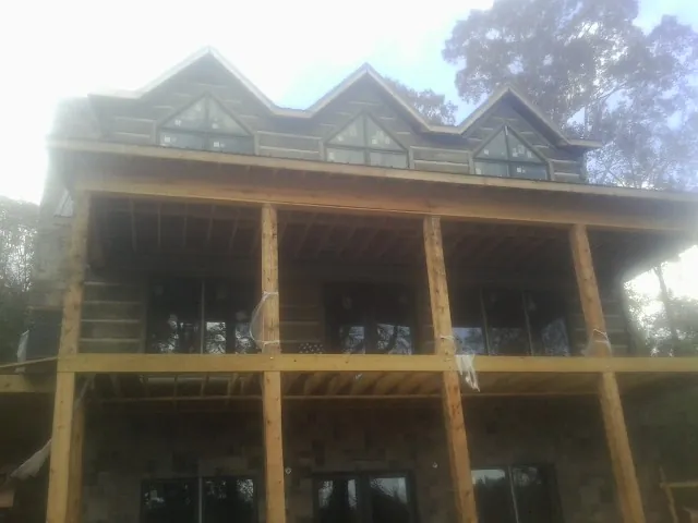 Dormers and porch framing on a large log home under construction — Roof Coating work by our crew in Mcville