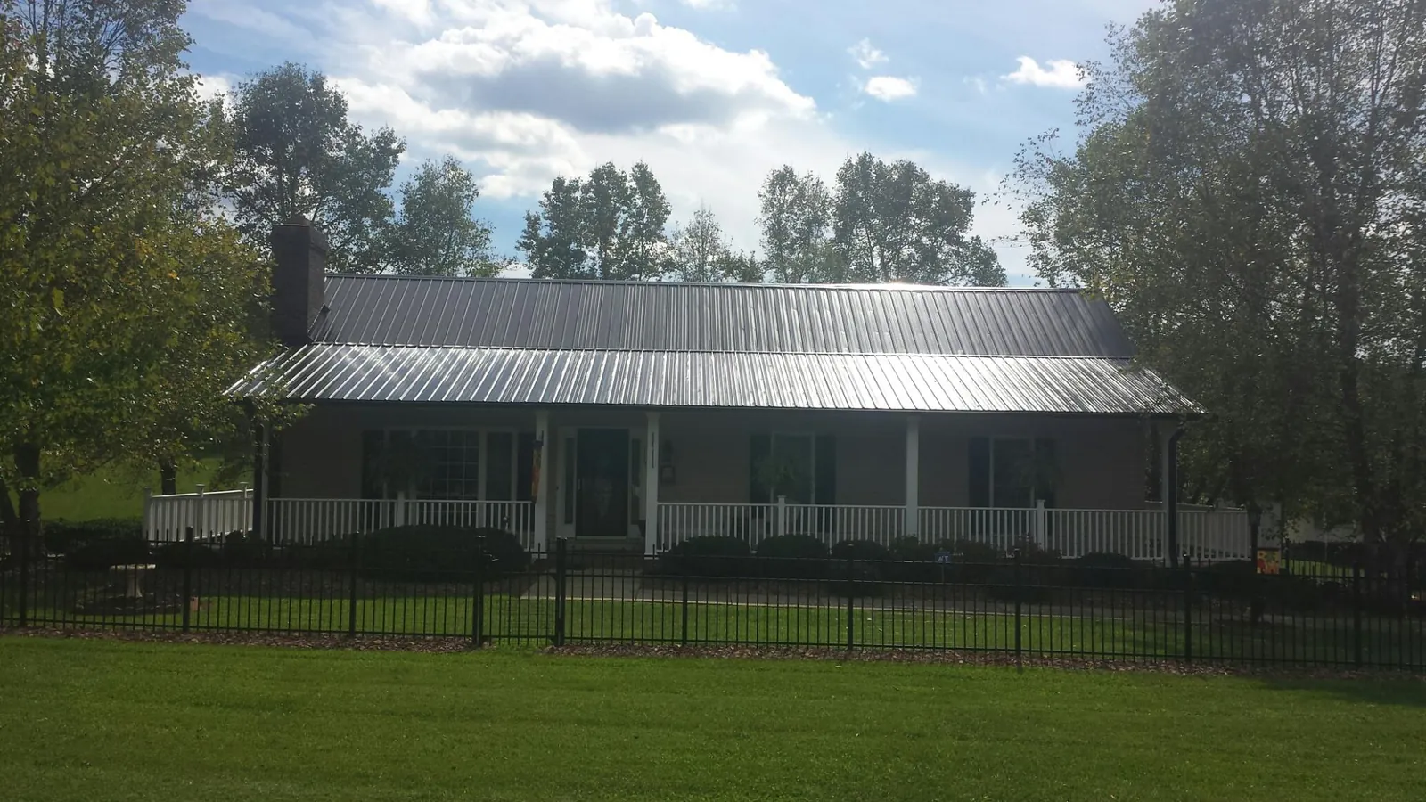 Gray metal roof on a brick ranch with a full width front porch — Gutter Guard Installation work by our crew in Mcville