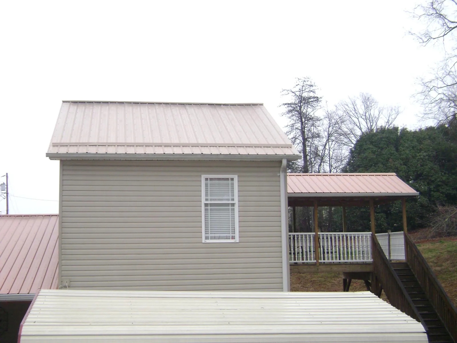 Tan metal roofs on a two story addition and attached porch, from a Roof Replacement job in Mcville