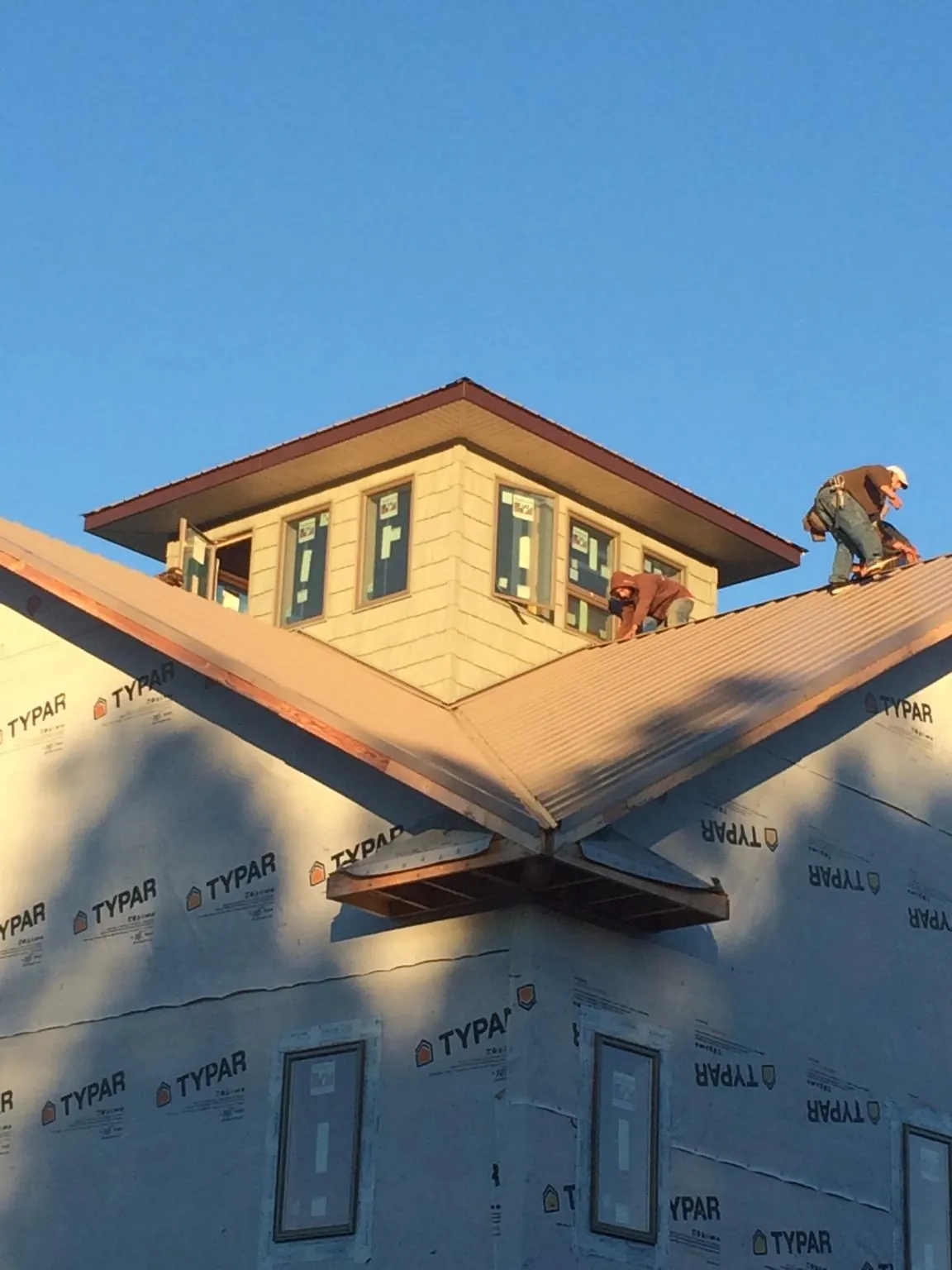 Roofers working around a rooftop cupola on a new metal roof at sunset — Roof Waterproofing in Mcville by Roofing Brothers